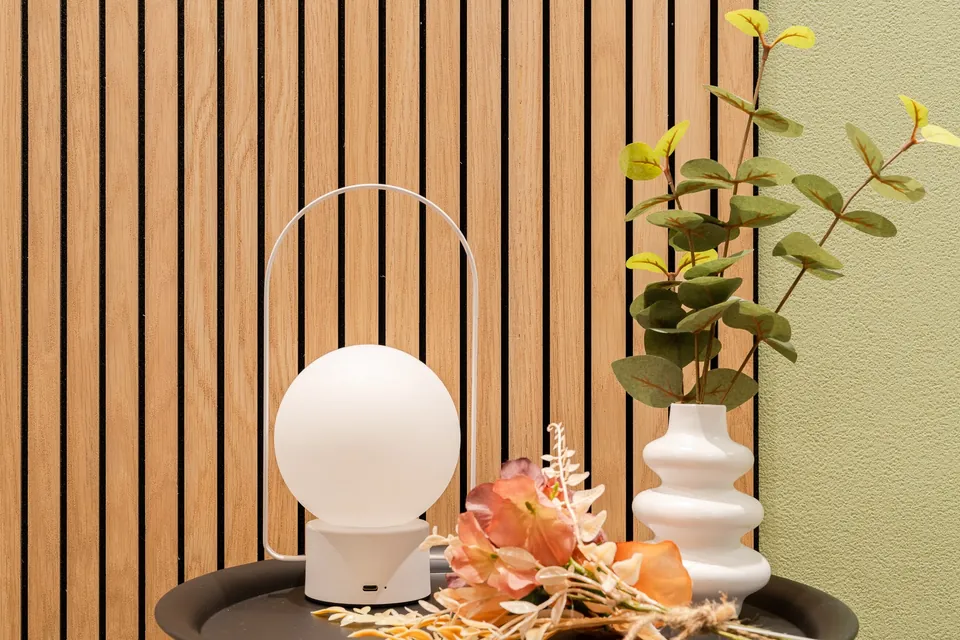 品川の客室にある、丸い白いランプと波形の花瓶。木のルーバーとオリーブ色の壁